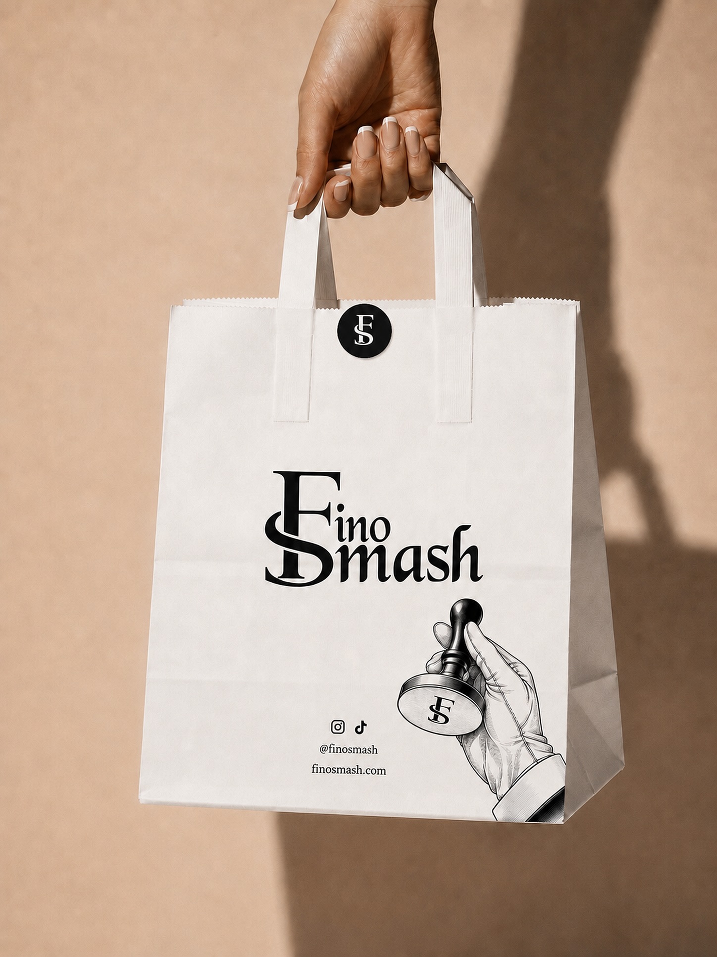 FinoSmash campaign: a FinoSmash paper bag printed with the hand-and-presser mark, held against a warm neutral wall
